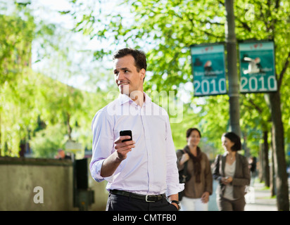 Glücklicher Mann hält Handy und wegsehen Stockfoto