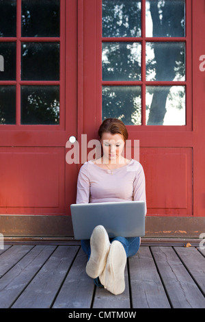 Frau sitzt vor der Tür und mit laptop Stockfoto