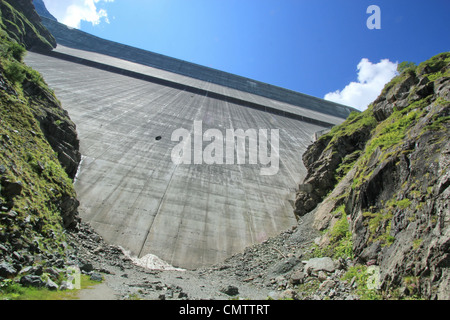 Ansicht der Grande Dixence Staumauer von unten neben großen Felsen bei sonnigem Wetter, Schweiz Stockfoto