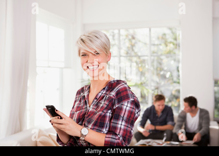Junge Frau hält Telefon und Blick in die Kamera Stockfoto