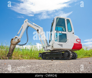 Kleine Raupe Traktor steht auf dem Asphalt gegen den blauen Himmel Stockfoto