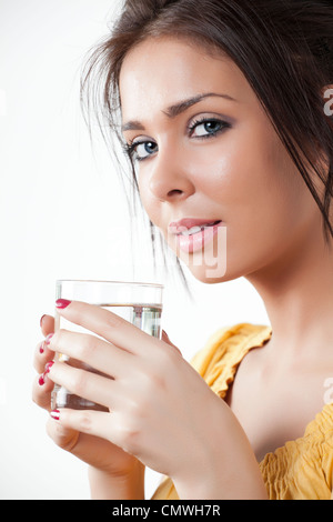 Junge Frau hält ein Glas Wasser und schaut in die Kamera Stockfoto