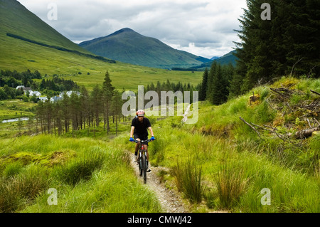 Mountainbiker auf dem West Highland Way Schottland, oberhalb von Bridge of Orchy mit Beinn Odhar hinter Stockfoto