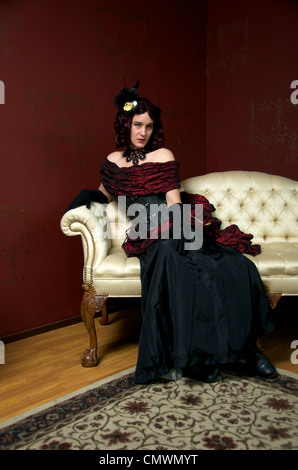 Eine Dame gekleidet in viktorianischen Steampunk Outfit auf weiße Couch. Stockfoto