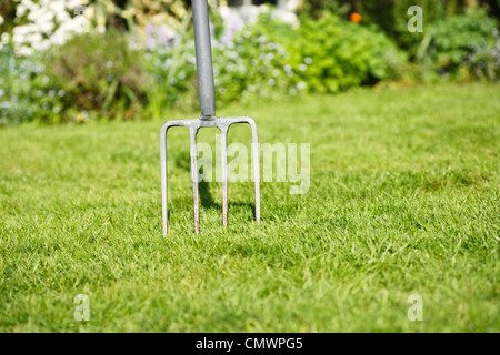 Garten Rasen mit einer Gabel stecken in dem Rasen Vertikutieren den Rasen darzustellen Stockfoto