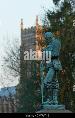 Statue eines Soldaten bei Sonnenuntergang in Christchurch Park mit Pfarrkirche St. Margaret nach hinten, Ipswich, England Stockfoto