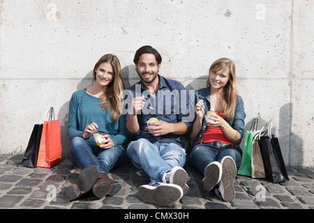 Deutschland, Köln, junger Mann und mit Eis und Einkaufstaschen, Lächeln, Porträt Stockfoto