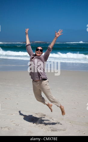 Frau am Strand in die Luft springen Stockfoto