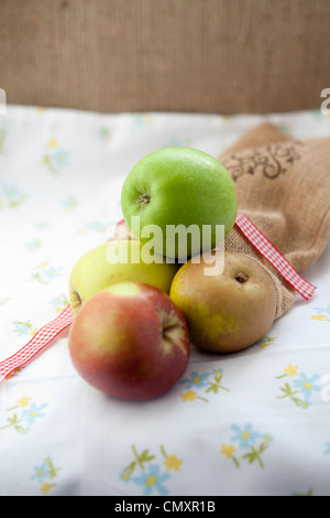 Äpfel mit einer hessischen Tasche in natürlichem Licht. Auswahl an Obst, einschließlich Cox, Braeburn, Granny Smith, Golden Delicious, Jazz. Stockfoto