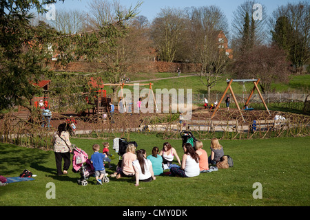 Menschen in einem Park - Gruppe von Müttern und Kleinkindern in der Sonne im Park, Abbey Gardens, Bury St. Edmunds, Suffolk UK Stockfoto