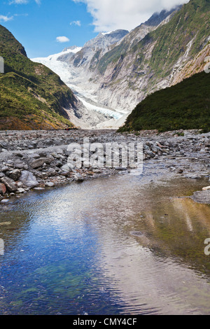 Franz Josef Glacier, West Coast, New Zealand, spiegelt sich in einem Bach im Tal. Stockfoto