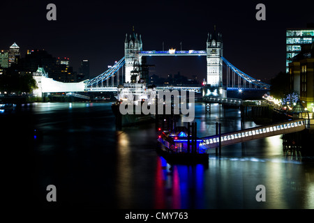Tower Bridge bei Nacht mit glatten Reflexionen in der Themse. Die Brücke ist mit Lichtern beleuchtet Stockfoto