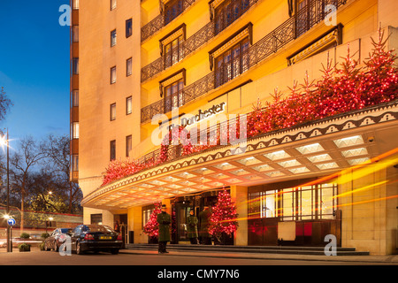 Das Dorchester Hotel Park Lane London mit Weihnachtsschmuck in der Abenddämmerung. Fünf-Sterne-Luxushotel, Eingang, Portier in der Nacht. Stockfoto