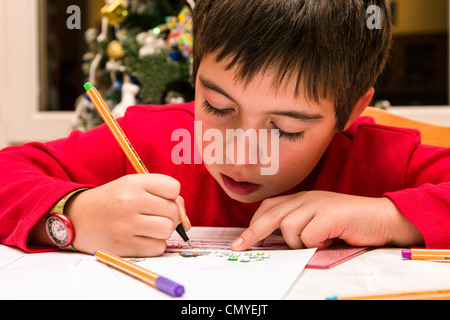 Kleiner Junge konzentrierte sich auf die Herstellung einer Zeichnung in der Weihnachtszeit Stockfoto