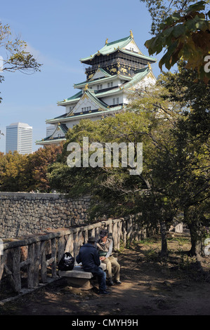 zwei japanische Männer sitzen auf Steinbank im Park am Osaka-Jo Burg, Osaka, Japan Stockfoto
