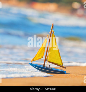 Das kleine Spielzeugboot steht am Sandstrand Stockfoto