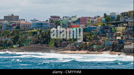 Bunte Häuser und Gebäude drängen sich am Hang entlang der Küste auf dem Ansatz zum Hafen von San Juan in Puerto Rico. Stockfoto