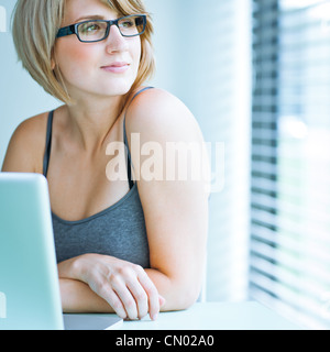 Porträt einer jungen Frau nachdenklich Blick aus dem Fenster, während Sie sitzen vor ihrem laptop Stockfoto
