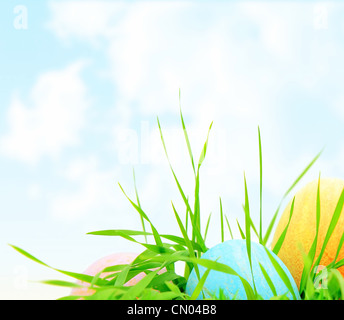 Ostern bunten Eiern Grenze mit frischem Grün grass über natürliche blaue Himmelshintergrund, traditionellen christlichen Frühlingsdekoration Stockfoto