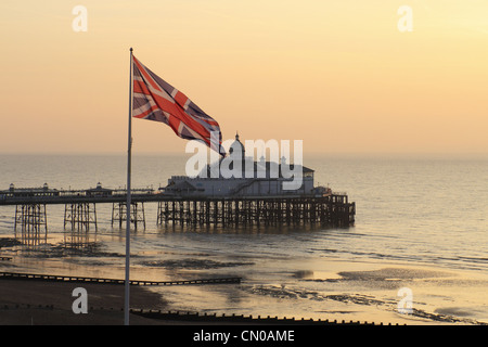 Der britische Union Jack-Flagge auf eine Fahnenstange mit Eastbourne Pier im Hintergrund, East Sussex, England. Stockfoto