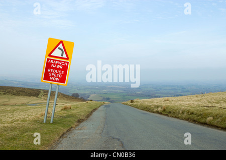 Arafwch Nawr, verringern Geschwindigkeit jetzt Straßenschild eine walisische Landschaft unterwegs. Stockfoto