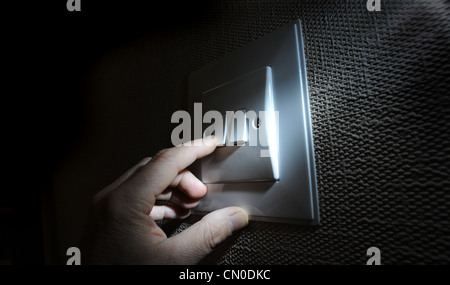 MANS HAND FINGER MIT INLÄNDISCHEN LICHTSCHALTER WIEDER STROM RECHNUNGEN TREIBSTOFFKOSTEN DER UMGEBUNG ELEKTRISCHE FOSSILEN BRENNSTOFFEN AUSSCHALTEN Stockfoto