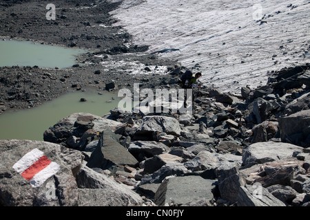 Walker auf Haute Route am Rande des Glacier de Prafleuri mit Haute Route Beschilderung (rot-weiß lackierten Stirpe). Stockfoto