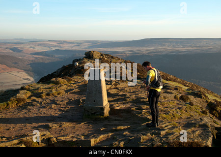 Ein fiel Läufer bei der trigonometrischen Punkt Gipfel Win Hill, in der Nähe von Hope, Peak District, Derbyshire, England, UK. Hope Valley hinter. Stockfoto