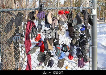 Verloren, Handschuhe und Hüte, die von einem Park Pfad, der einem Maschendrahtzaun befestigt Stockfoto