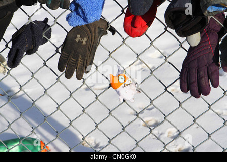 Verloren, Handschuhe und Hüte, die von einem Park Pfad, der einem Maschendrahtzaun befestigt Stockfoto