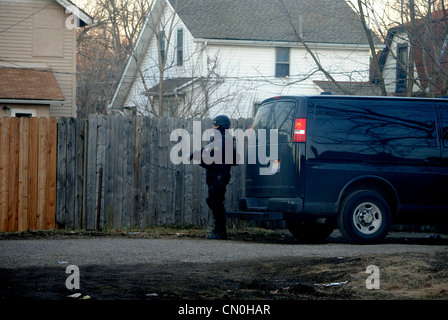 SWAT Officer, sichert Hintereingang, während einer Drogenrazzia, mit Waffen ausgestattet. Stockfoto