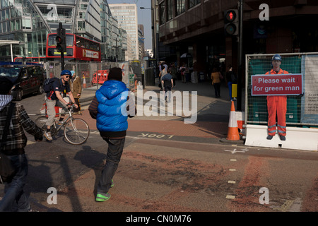 Junge Männer Strich vor nähert sich Radfahrer an einer Kreuzung im Zentrum von London in der Nähe von Miniatur-Arbeiter Warnung. Stockfoto