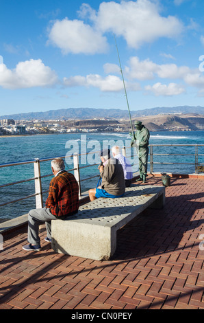 Drei ältere spanische Männer sitzen auf der Bank am La Puntilla am östlichen Ende von Las Canteras Strand in Las Palmas, Gran Canaria Stockfoto