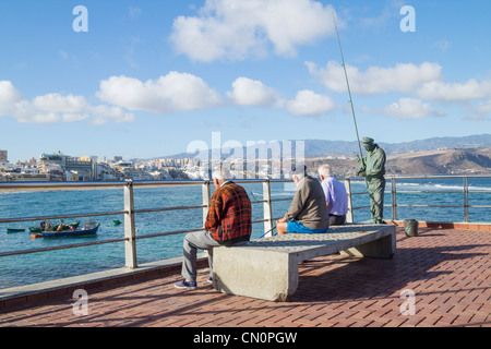 Drei ältere spanische Männer sitzen auf der Bank am La Puntilla am östlichen Ende von Las Canteras Strand in Las Palmas, Gran Canaria Stockfoto