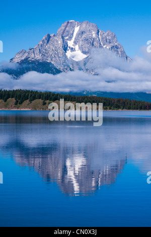 Reflexionen und tief liegende Wolken am Mount Moran und Jackson Lake im frühen Morgenlicht im Grand Tetons National Park in Wyoming. Stockfoto