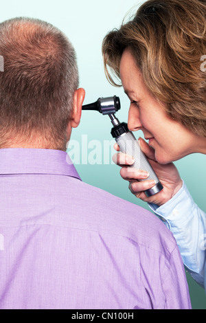 Foto von einer Ärztin untersucht eine Patienten Ohr mit einem Otoskop. Stockfoto