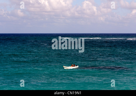 Kleines weißes Boot mit drei Personen in ihm allein auf ein riesiges Meer der Karibik. Stockfoto