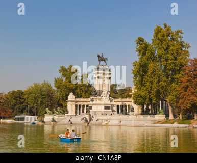 Madrid, Spanien. Rudern auf dem Estanque oder See, in El Retiro Gärten. Denkmal für König Alfonso XII im Hintergrund. Stockfoto