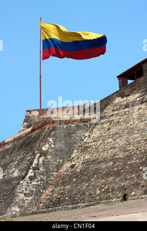 Kolumbianische Flagge Bäche im Wind über den verwitterten Mauern des Castillo San Felipe de Barajas in Cartagena de Indias, Kolumbien. Stockfoto