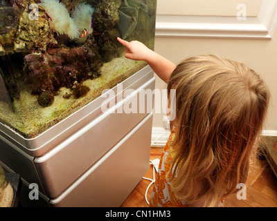 Junges Mädchen sucht einen Fisch In Salzwasser Aquarium zeigt auf Clownfische Stockfoto