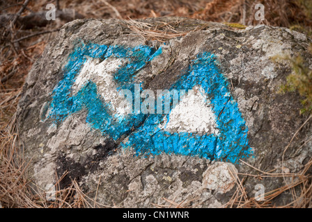 Wandern, Schilder, Pfeil und Dreieck, gemalt in blau und weiß auf einem Felsen Stockfoto