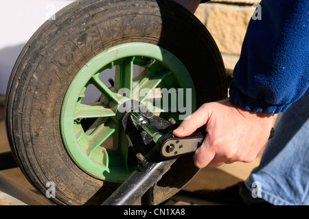 Ein Mann verwendet einen Steckschlüssel, das Rad aus einem Garten Grabhügel zu entfernen Stockfoto