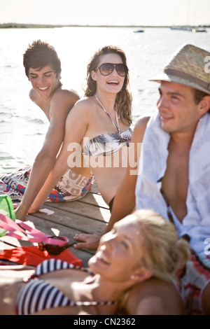 Zwei junge Paare sitzen und Sonnenbaden am Rande des Pier Stockfoto