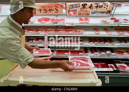 Ein Mitarbeiter Aktien Regale mit Packs vom Wagyu-Rind an einem Seitenarm des Uny Supermarkt in Nagoya, Japan. Stockfoto