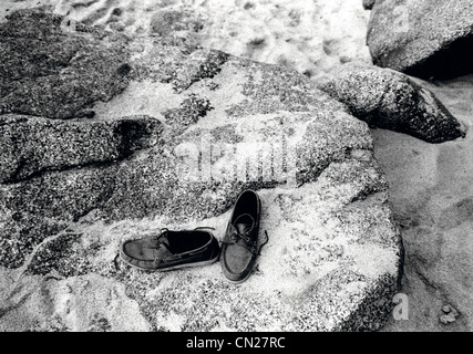 Paar Schuhe auf Felsen am Strand Stockfoto