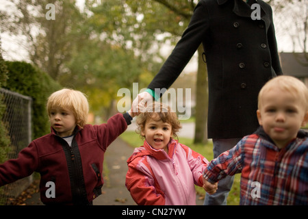 Frau mit drei Kindern zu Fuß entlang der Fahrbahn Stockfoto