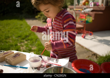 Kleinkind Mädchen spielen mit Farben außerhalb Stockfoto