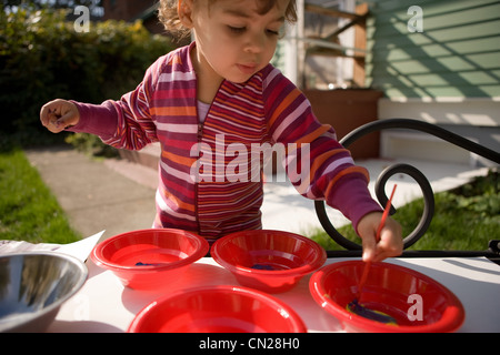 Kleinkind Mädchen spielen mit Farben außerhalb Stockfoto