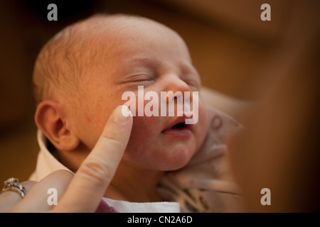 Mutter rührende Neugeborenen jungen Gesicht mit finger Stockfoto