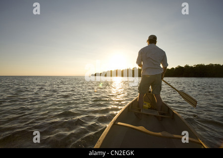 Mann stehen und paddeln Boot bei Sonnenuntergang, Florida Keys, USA Stockfoto